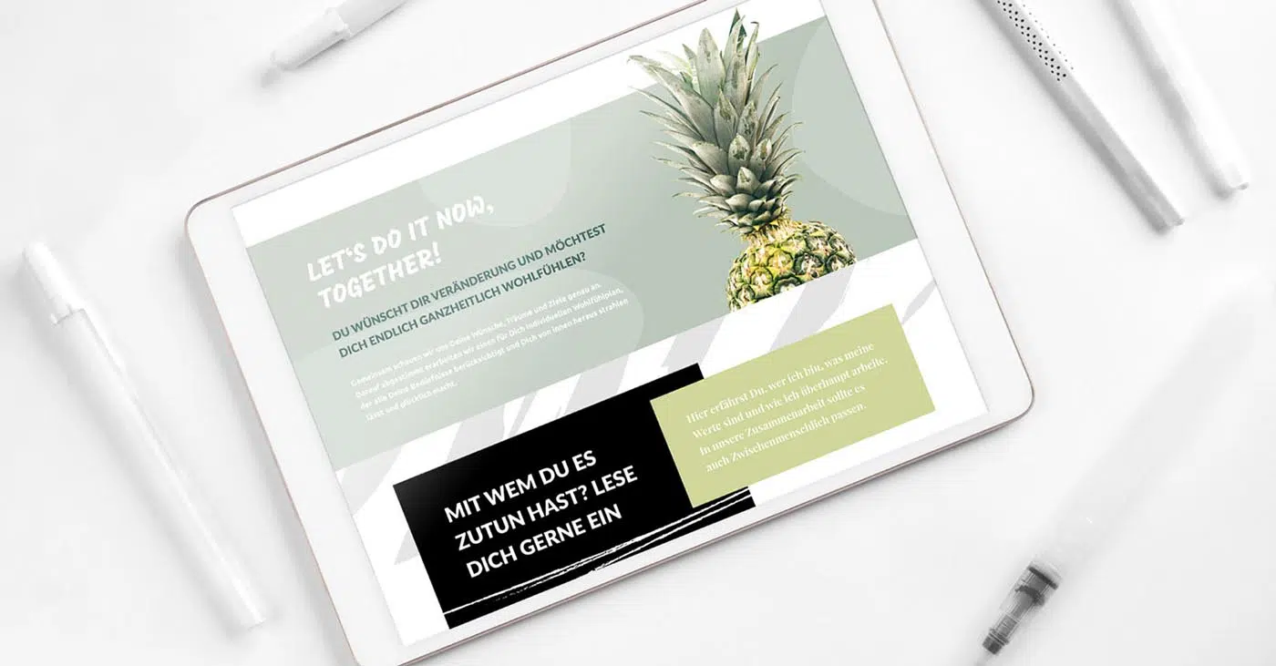 Hintergrund weiß mit diversen weißen und transparenten Stiften. Im Vordergrund Tablet mit Layout einer Webseite in salbei in der oberen Hälfte und weiß-grau in der unteren Hälfte. Die Kernaussage findet sich in einem Schwarzen Rechteck wieder. Daneben in hellgrün ein weiteres Rechteck mit einem weiteren Text
